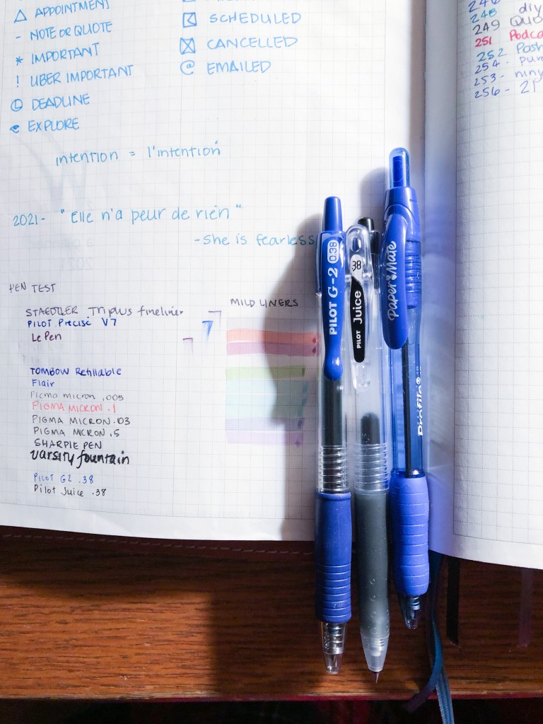 A photo of a planner with three pens side by side.